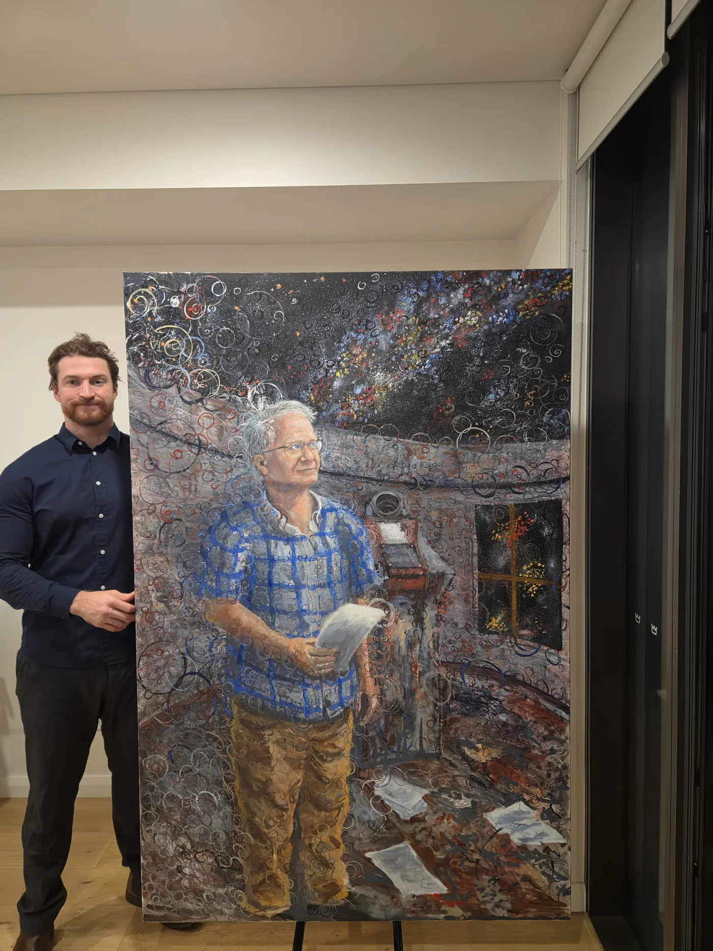 The Observer of Cosmic Expansion hung on a gallery wall with the artist standing beside it for scale
